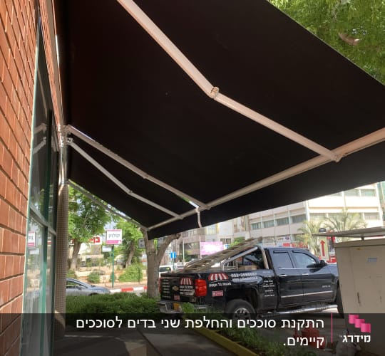 סוכך שחור עם מסגרת לבנה מחובר לקיר לבנים